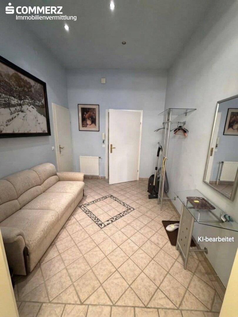 Geräumiger Raum mit Sofa, Fliesenboden und einem dekorativen Fliesenmuster in der Mitte.