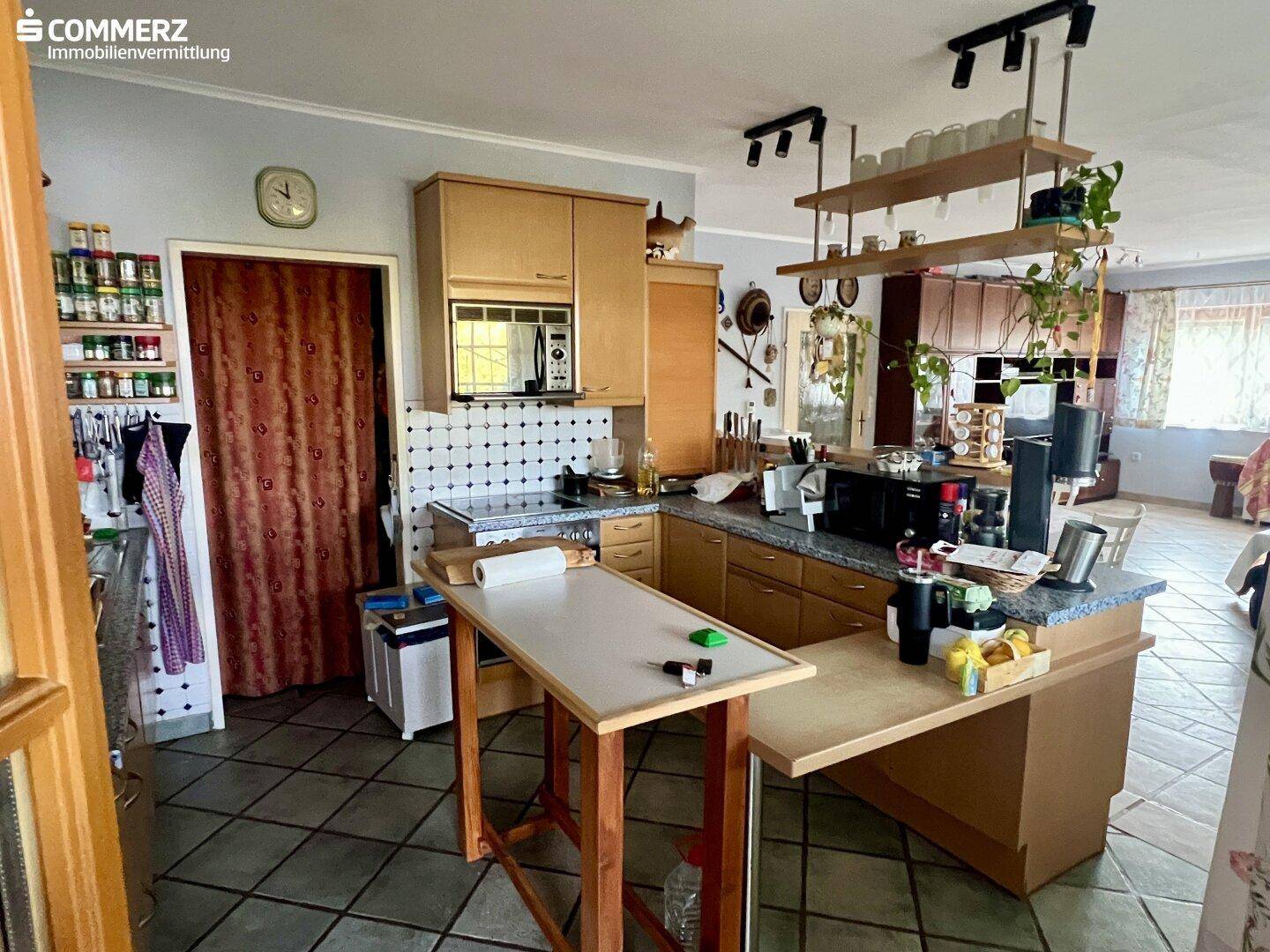 Funktionale Küche mit Holzschränken, gefliestem Boden und einer praktischen Frühstücksbar.