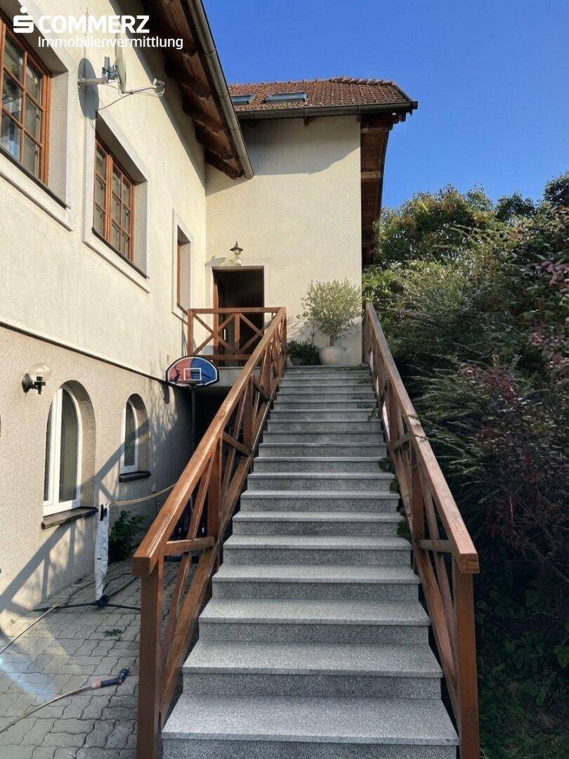 Lange Außentreppe mit Holzgeländer, die zum Eingang des Hauses führt.