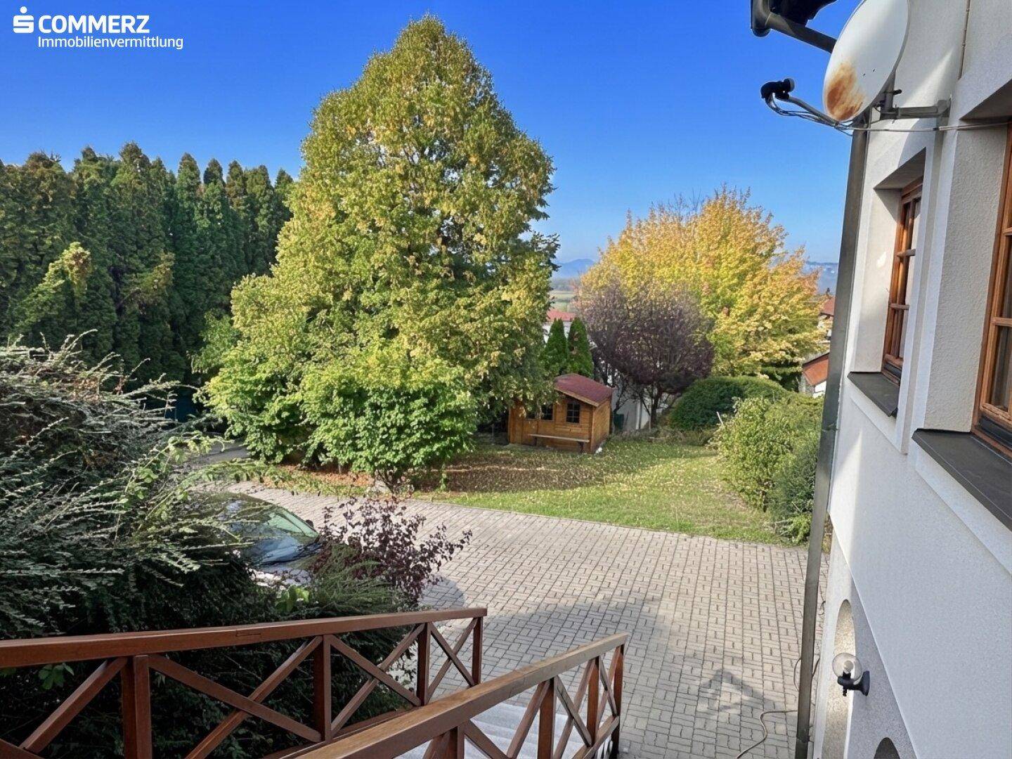 Blick von oben auf den Garten mit Holzschuppen und Bäumen, umgeben von viel Grün.