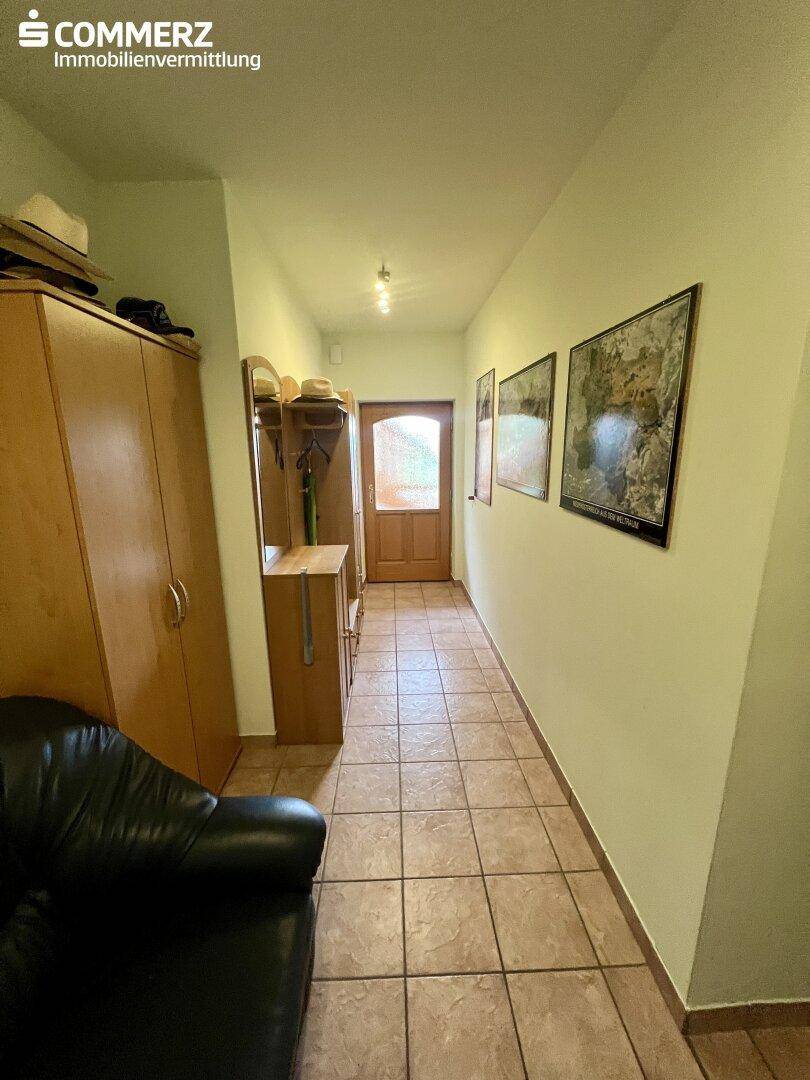 Eingangsbereich mit gefliestem Boden, Garderobe und Holztür, bietet einen freundlichen Empfang.