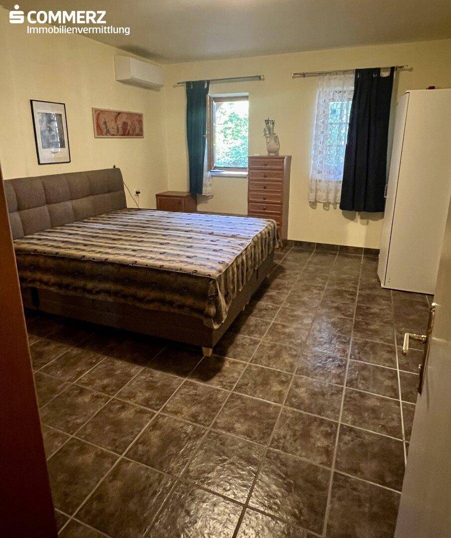 Schlafzimmer mit gefliestem Boden, Doppelbett und Klimaanlage für angenehme Temperaturen.
