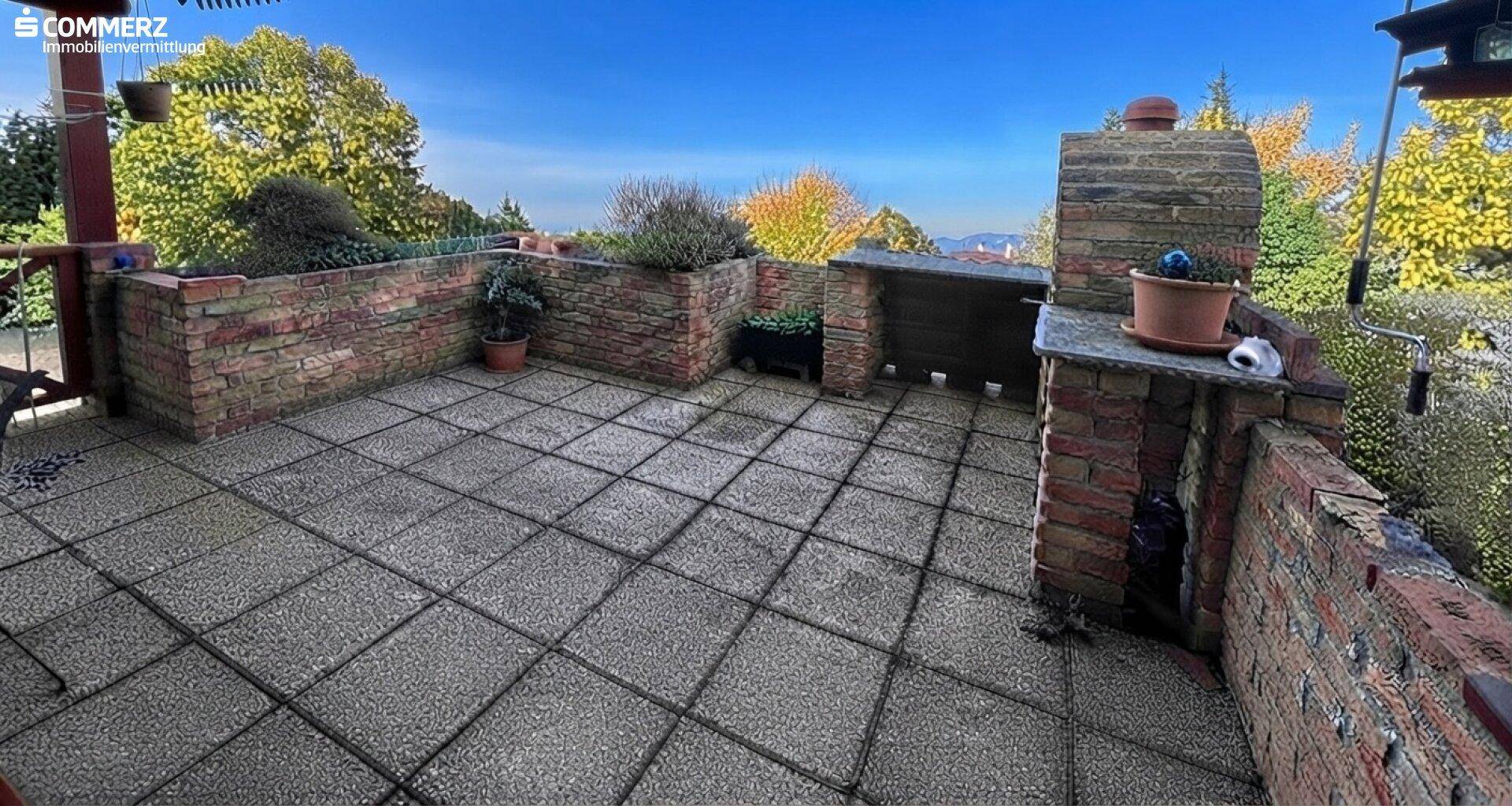 Gemütliche Terrasse mit gemauertem Grill und Pflanzbeeten, bietet einen schönen Ausblick in die Umgebung.