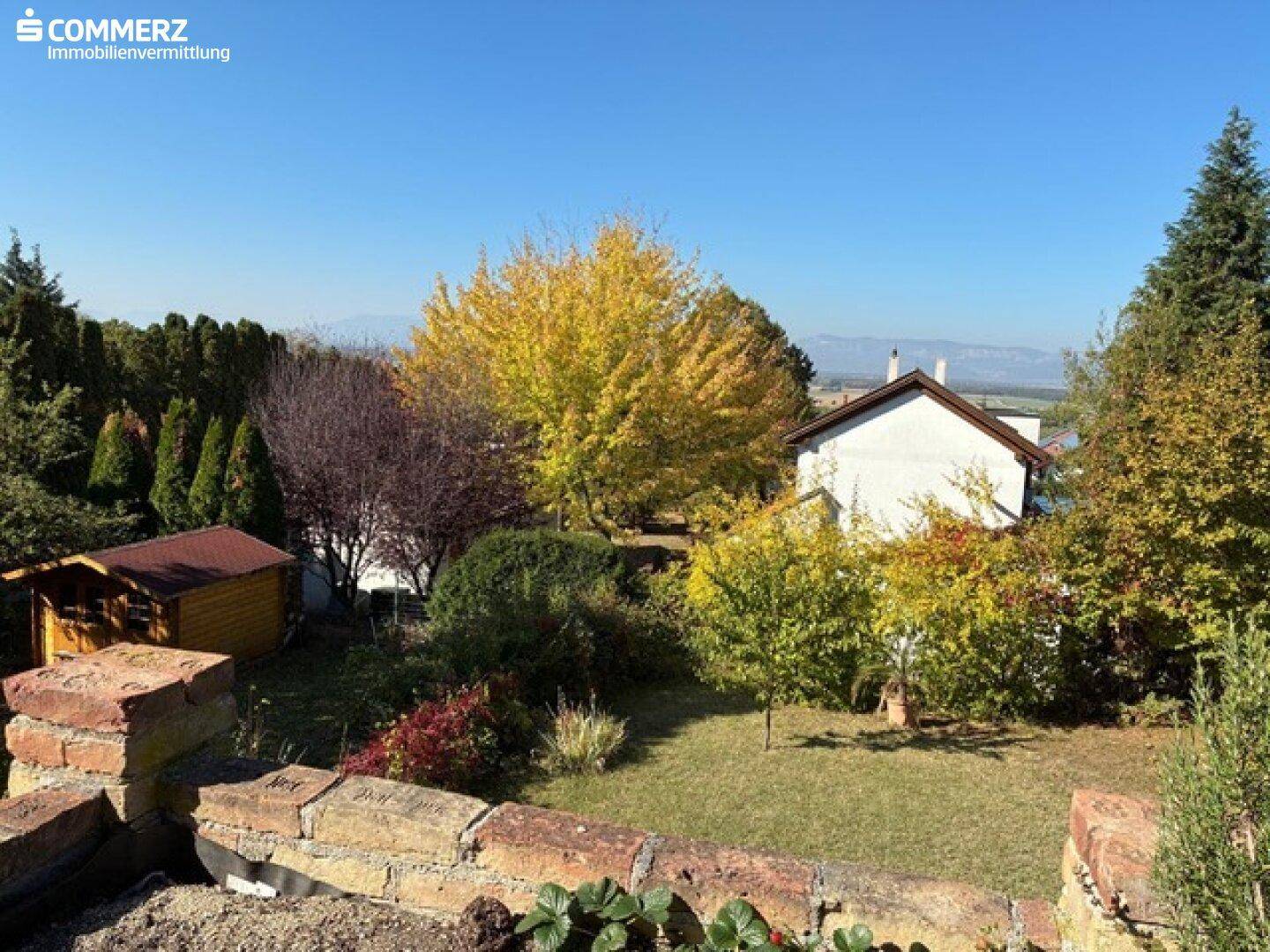 Weitläufiger Garten mit einem kleinen Holzschuppen und herbstlicher Vegetation, umgeben von Natur.