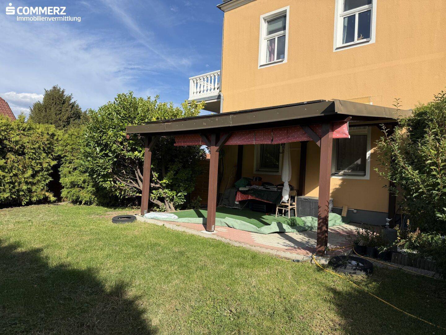 Gartenbereich mit überdachter Terrasse und Rasenfläche vor dem Haus.