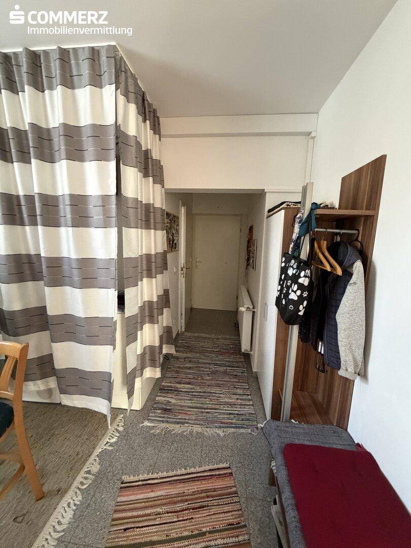 Eingangsbereich mit Garderobe und Vorhängen, die einen weiteren Raum abtrennen.