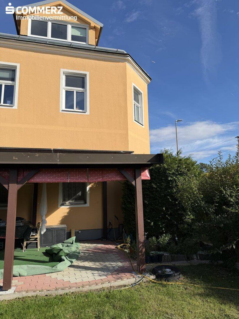 Seitenansicht des Hauses mit überdachter Terrasse und angrenzendem Gartenbereich.