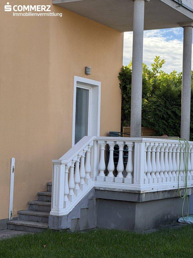 Eingangsbereich mit Steintreppe und klassischer Balustrade am Haus.