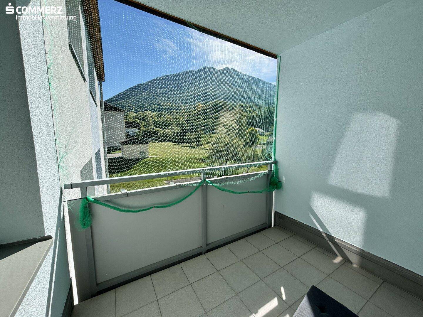 Balkon mit Fliesenboden und einem weiten Blick auf die umliegenden Berge und grüne Landschaft.