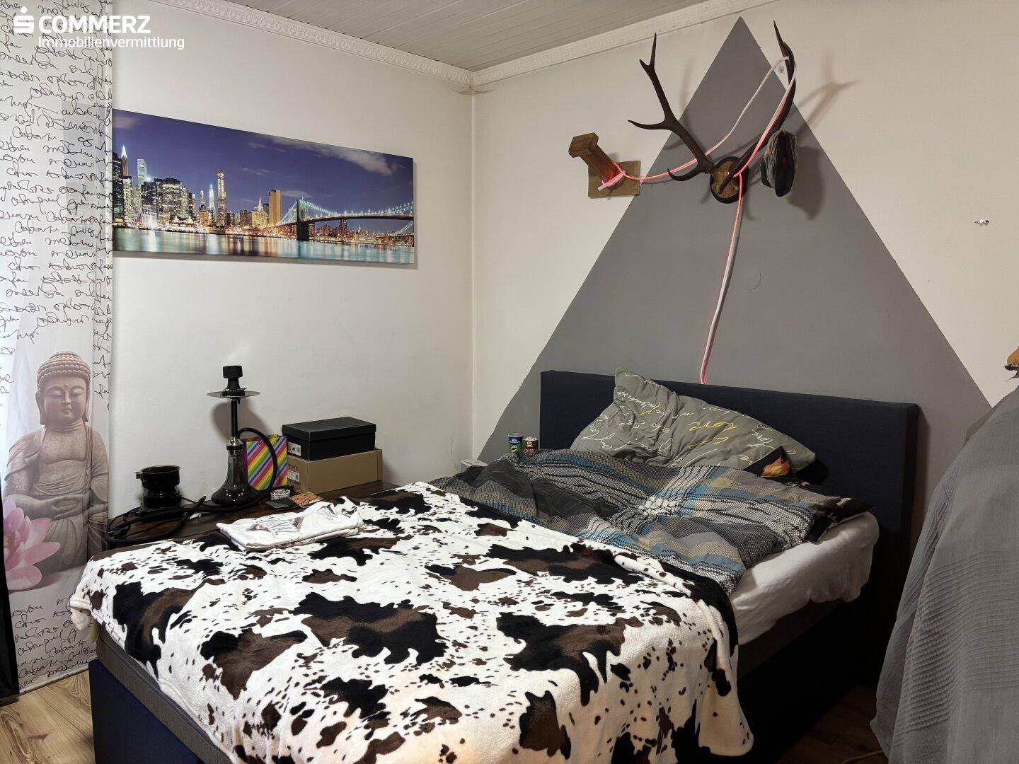 Schlafzimmer mit Doppelbett, auffälliger Wandgestaltung und Hirschgeweih-Dekoration.