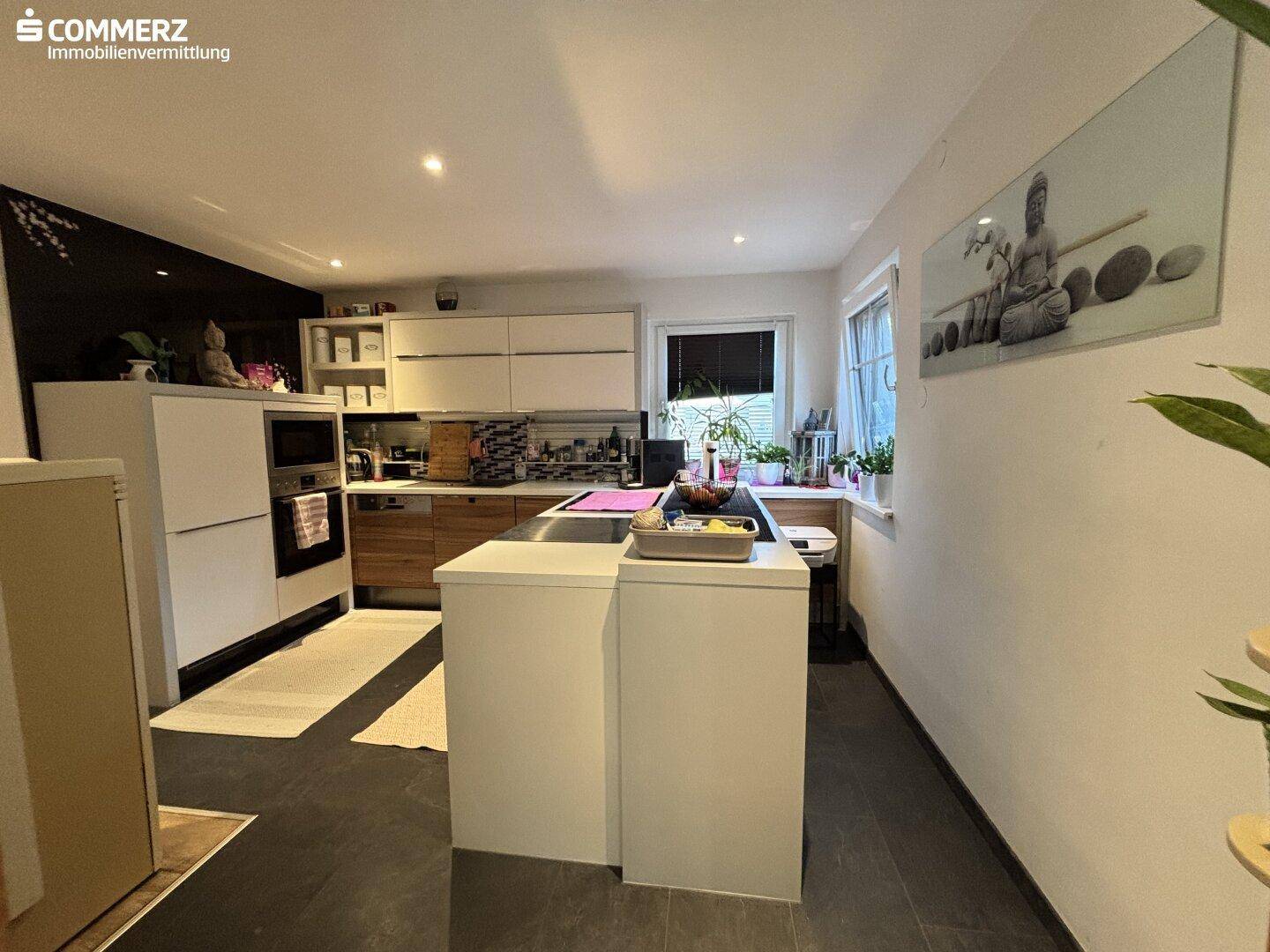 Moderne Küche mit weißen und holzfarbenen Schränken, Kochinsel und Einbaugeräten.
