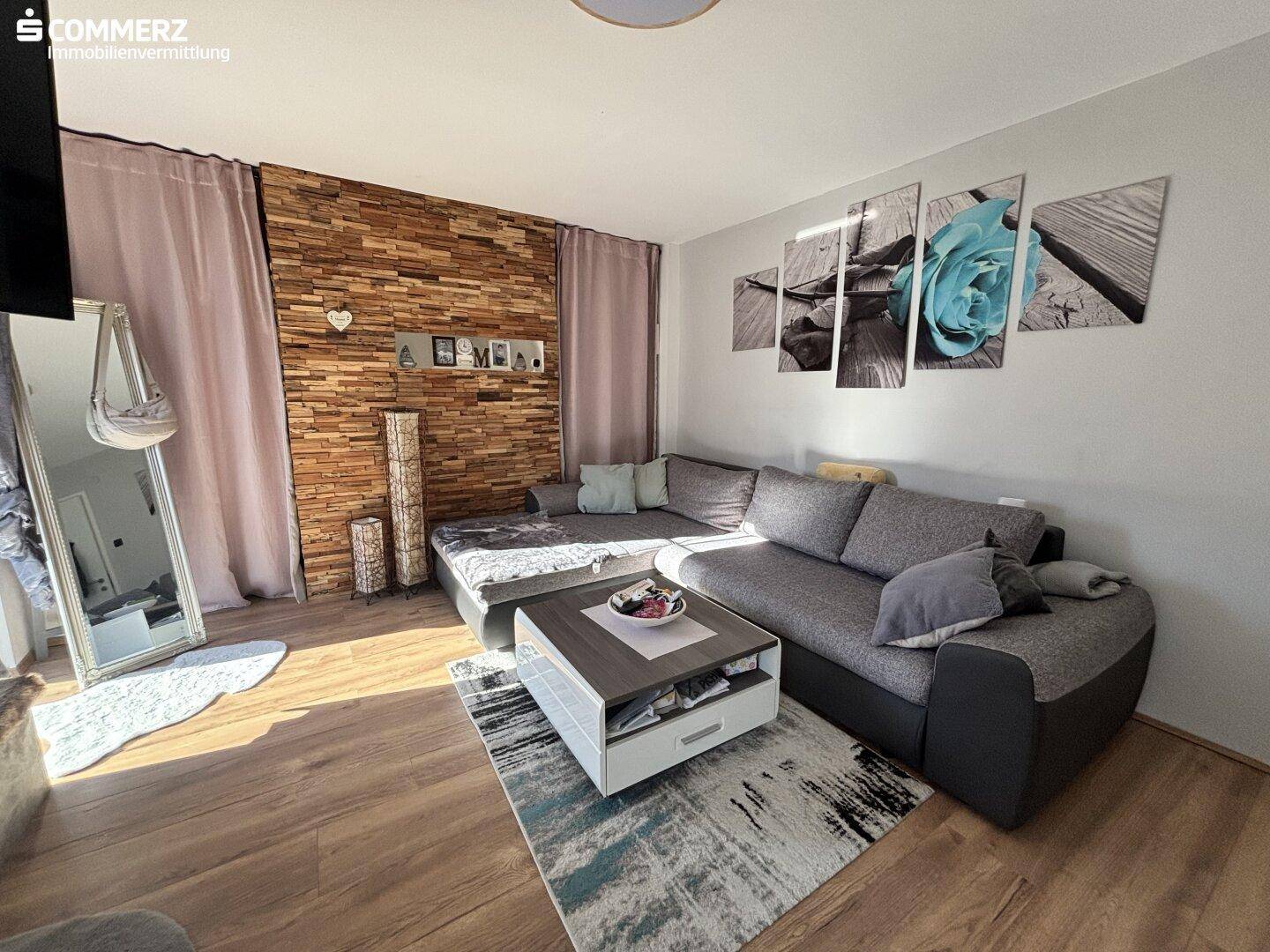 Wohnzimmer mit großem Ecksofa, Holzwandakzent und modernem Couchtisch.