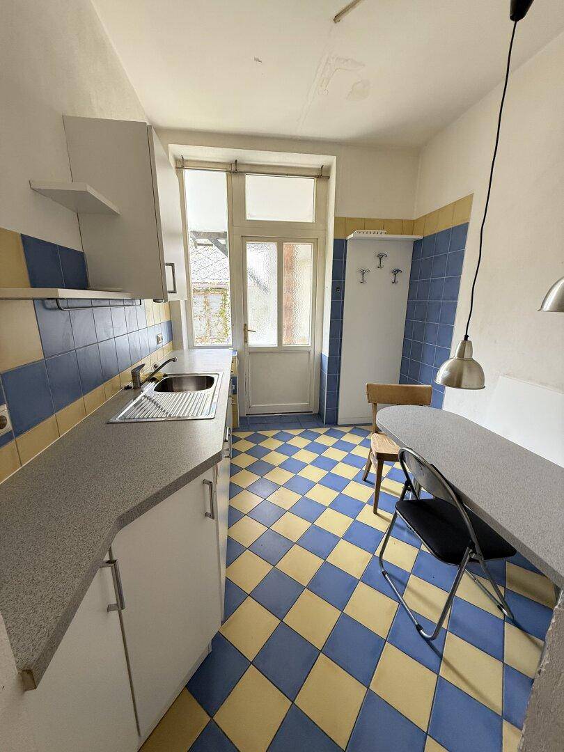 Küche mit blau-gelb kariertem Fliesenboden, Einbauschränken und Zugang zum Außenbereich.