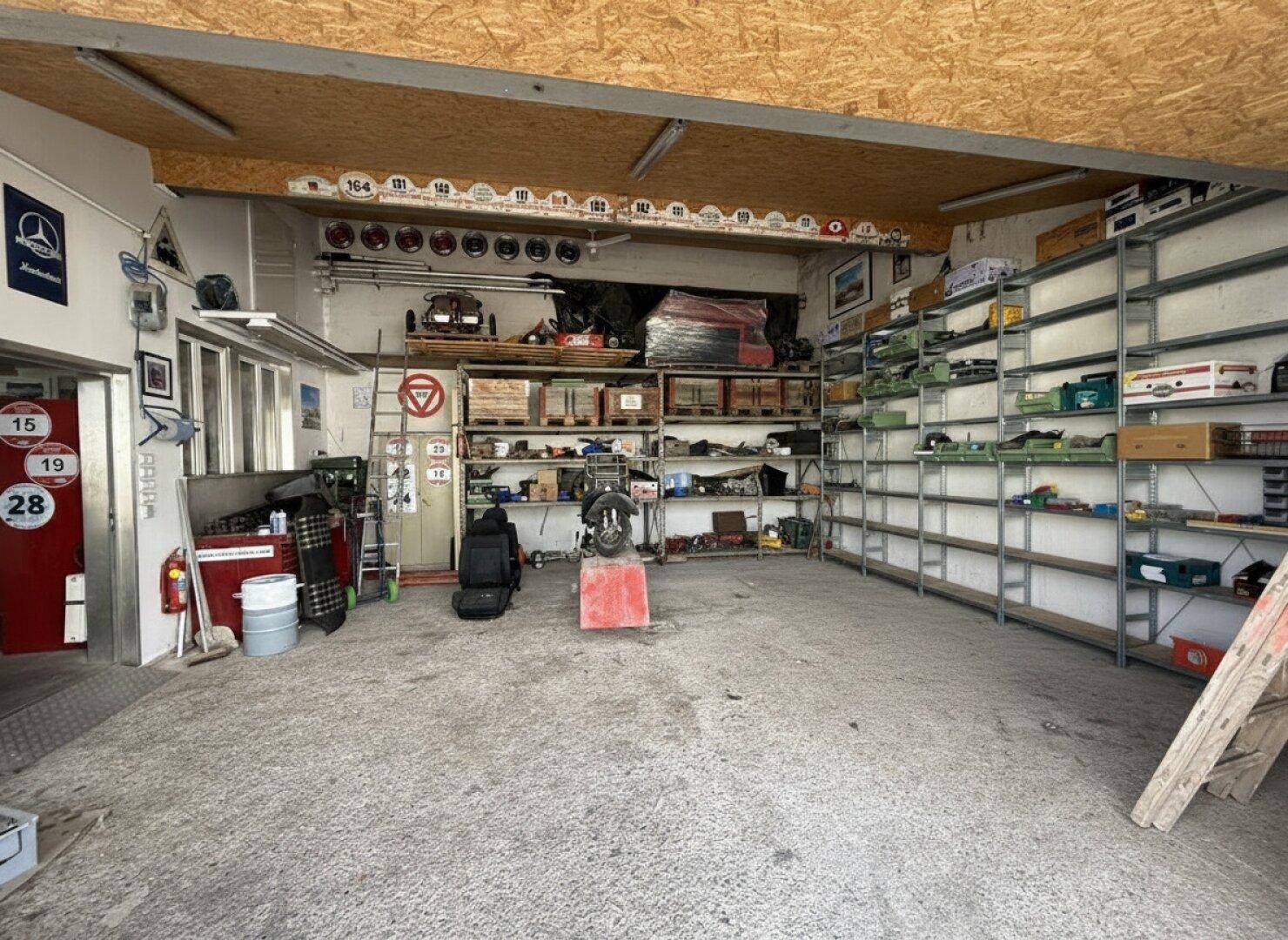 Geräumige Werkstatt mit umfangreichen Regalsystemen, Werkzeugen und einer Holzdecke, gut beleuchtet.
