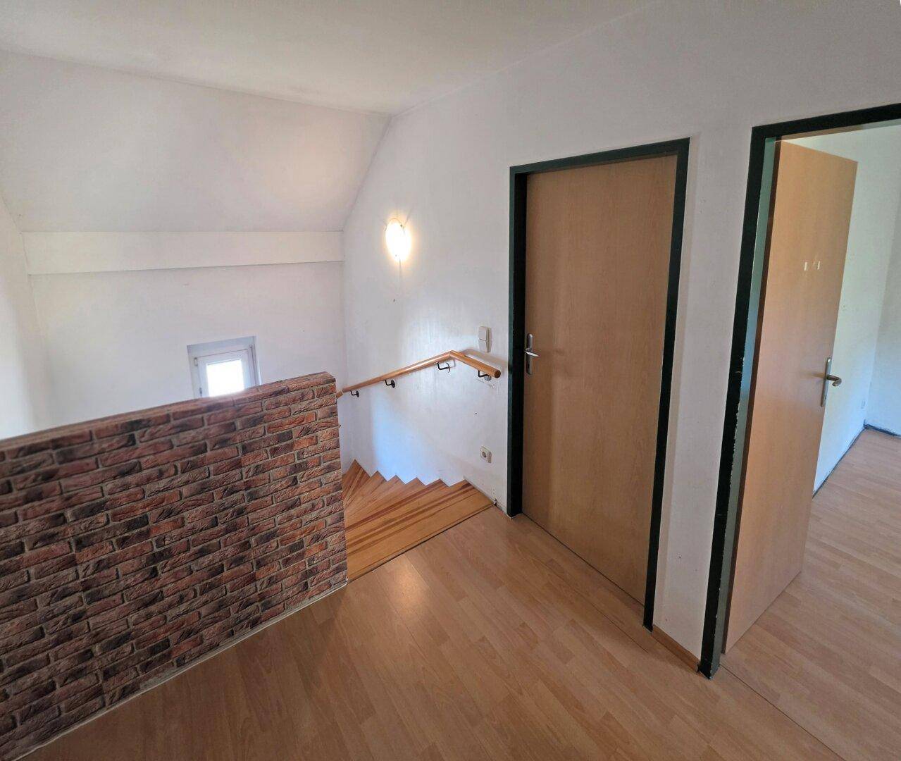 Heller Flur im Obergeschoss mit Holztreppe und Laminatboden.