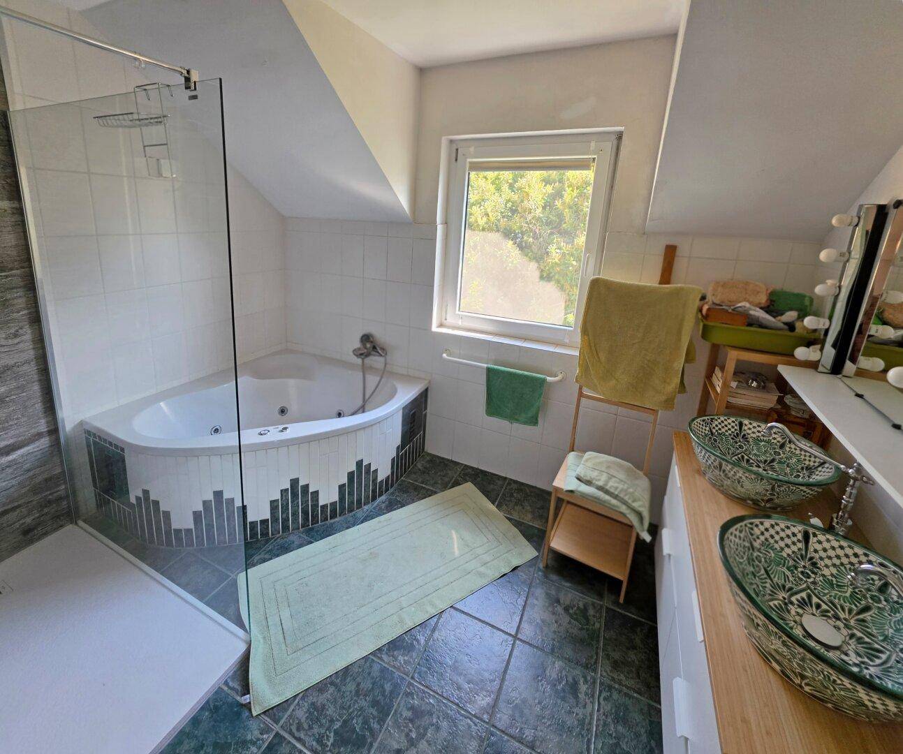 Badezimmer mit Eckbadewanne, separater Dusche, Doppelwaschbecken und Fenster.