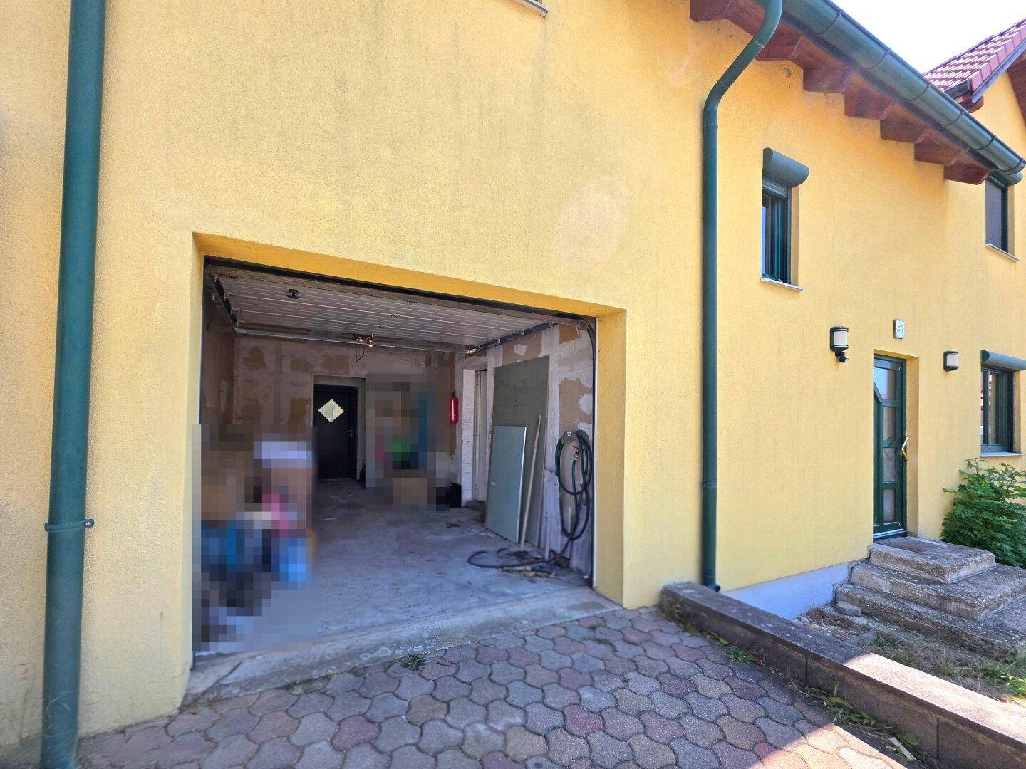 Offene Garage mit Betonboden und Blick in den dahinterliegenden Bereich.