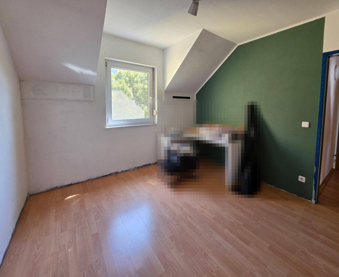 Helles Zimmer mit Dachschräge, Laminatboden und Blick ins Grüne, ideal als Büro.