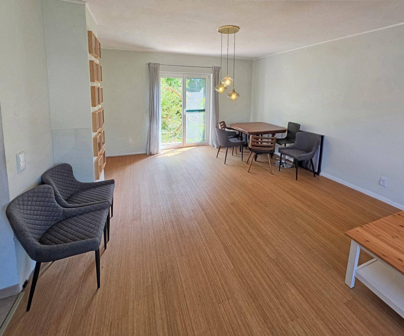 Heller Wohn- und Essbereich mit Laminatboden und Zugang zum Garten.