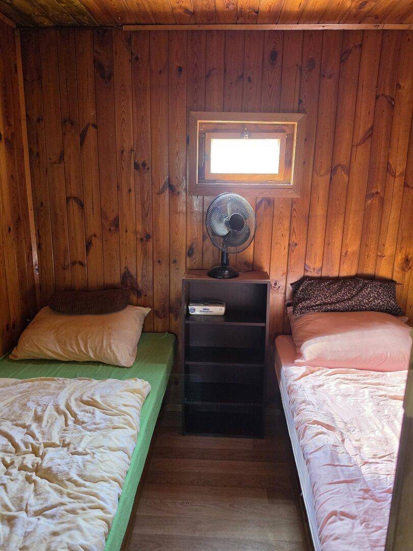 Schlichtes Schlafzimmer mit zwei Einzelbetten, Holztäfelung und kleinem Fenster.