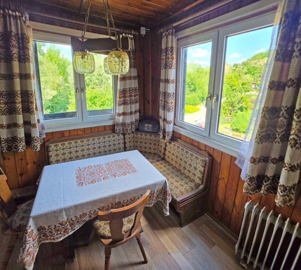 Gemütlicher Essbereich im Landhausstil mit Holztäfelung, Eckbank und Blick ins Grüne.