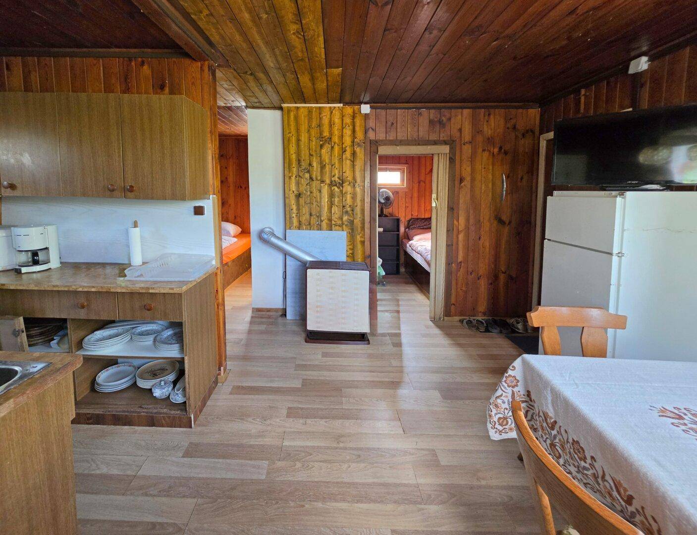 Rustikale Küche mit Holzschränken, Laminatboden und Durchgang zu weiteren Zimmern.