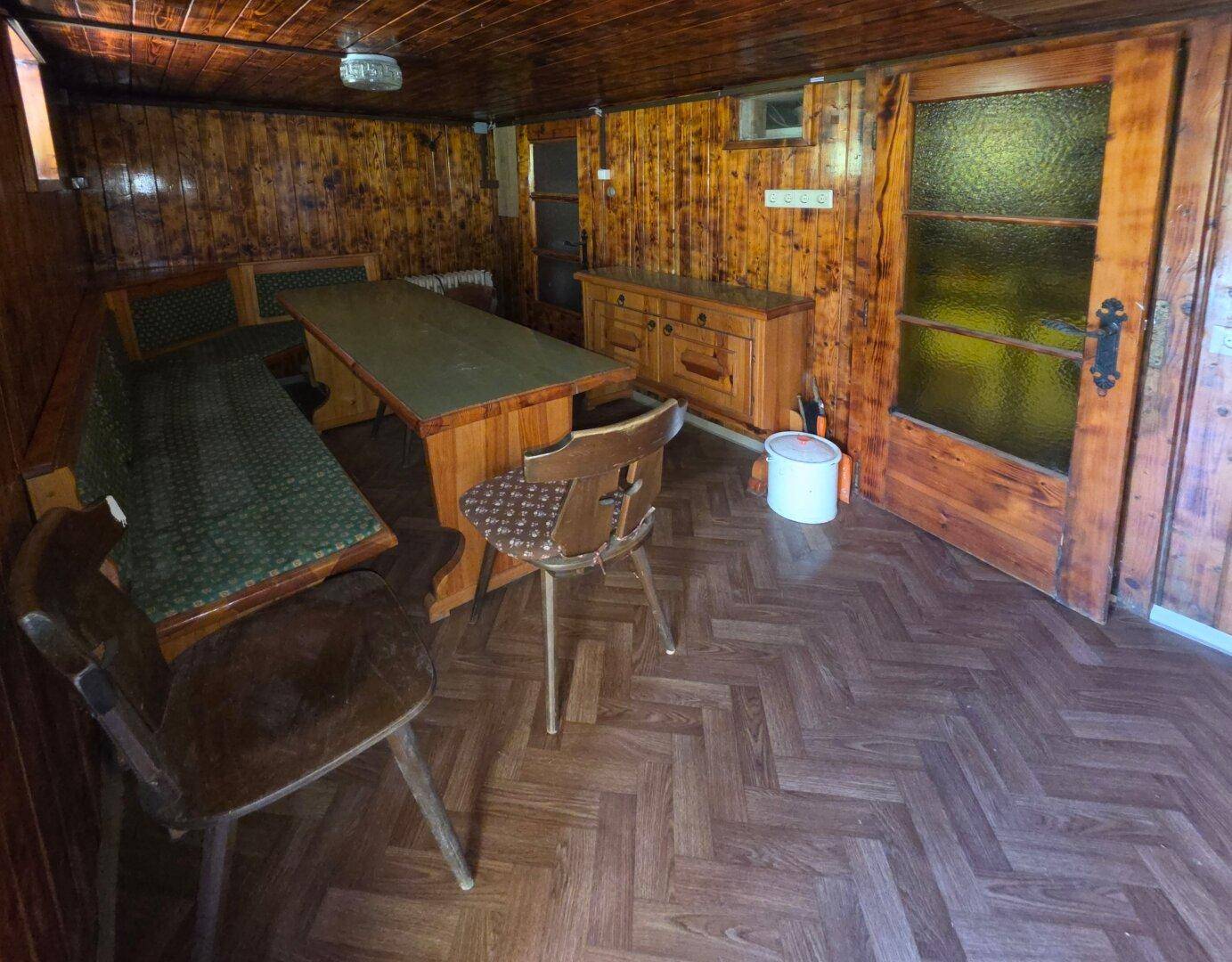Geräumiger Essbereich im Landhausstil mit großer Holztafel und Holztäfelung an Wänden und Decke.