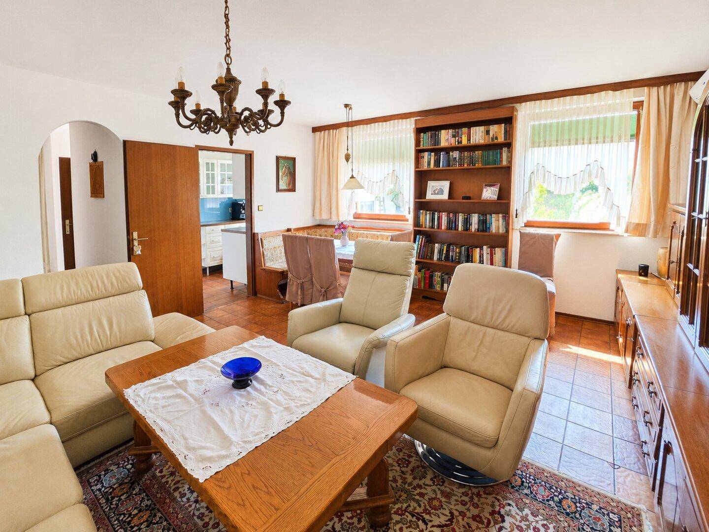 Klassischer Wohn-Essbereich mit Ledersofas, Holztisch und Bücherregal, mit Terrakottafliesen.
