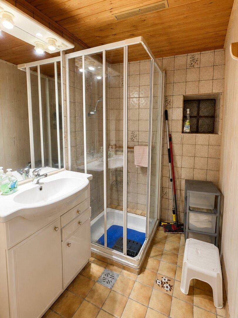 Badezimmer mit Duschkabine, Waschbecken und gefliesten Wänden und Boden.