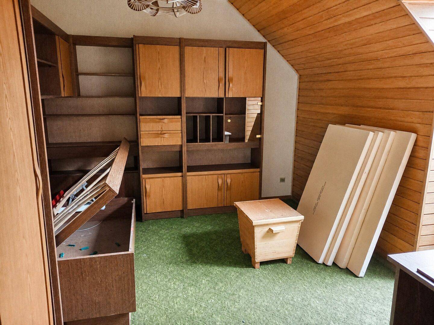 Dachzimmer mit Holzverkleidung, Teppichboden und Einbauschränken, ideal als Hobbyraum.