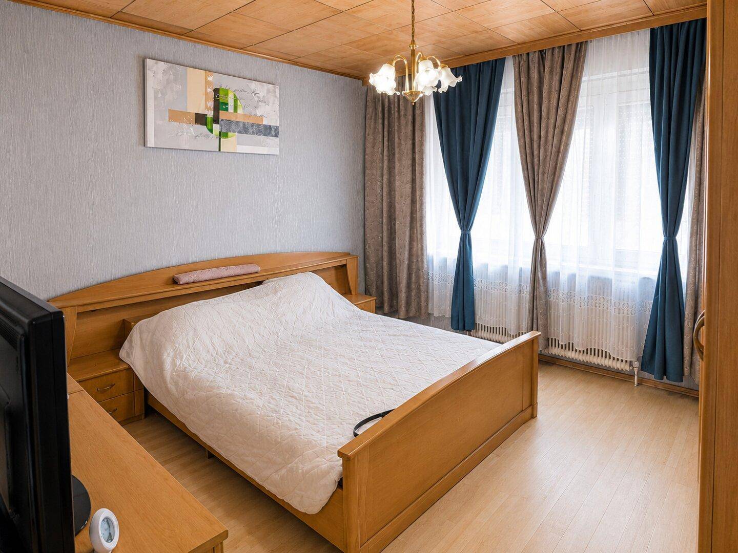 Gemütliches Schlafzimmer mit Holzbett, Holzdecke und Parkettboden.