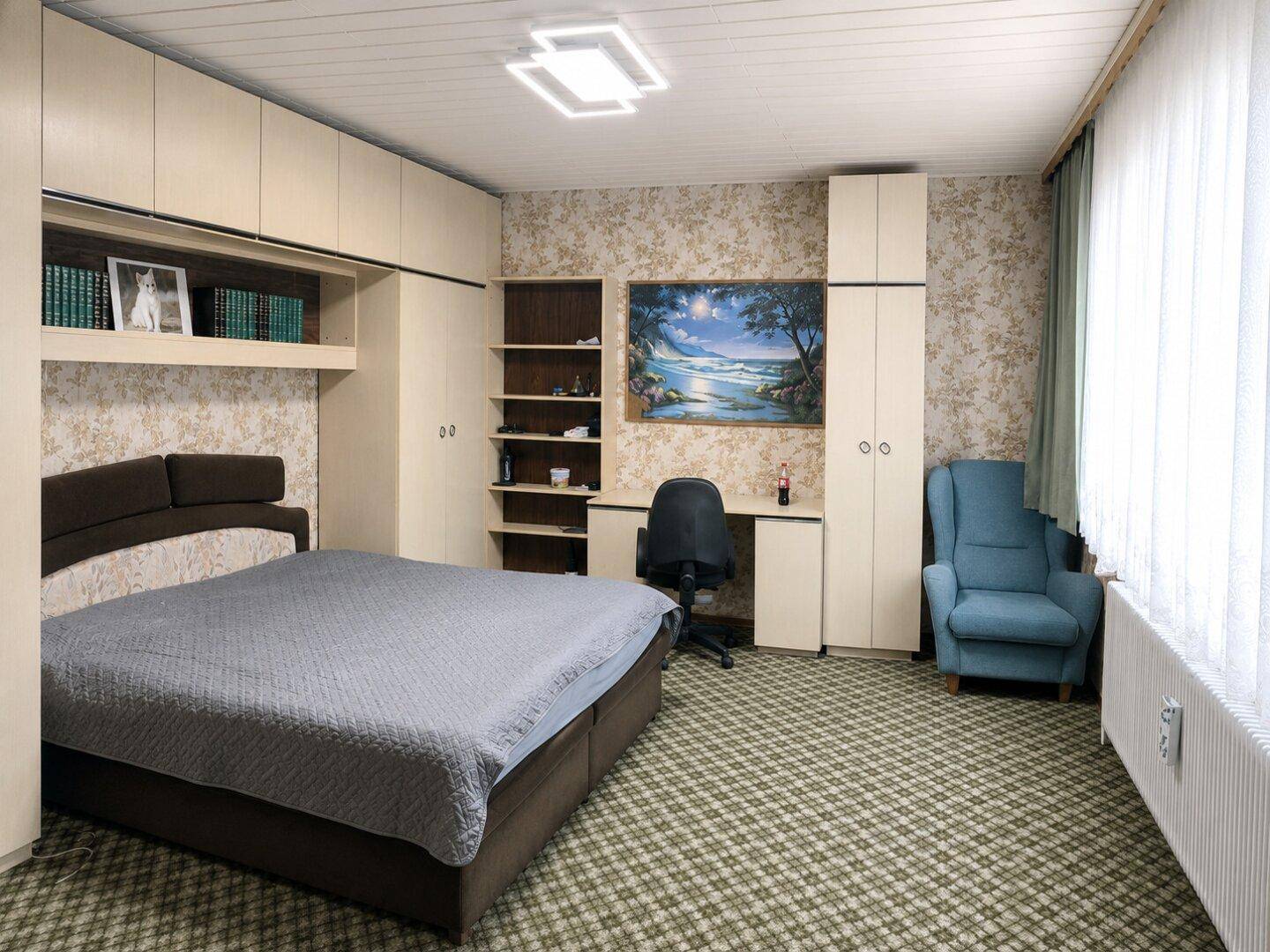 Schlafzimmer mit Teppichboden, Einbauschränken und Schreibtischbereich.