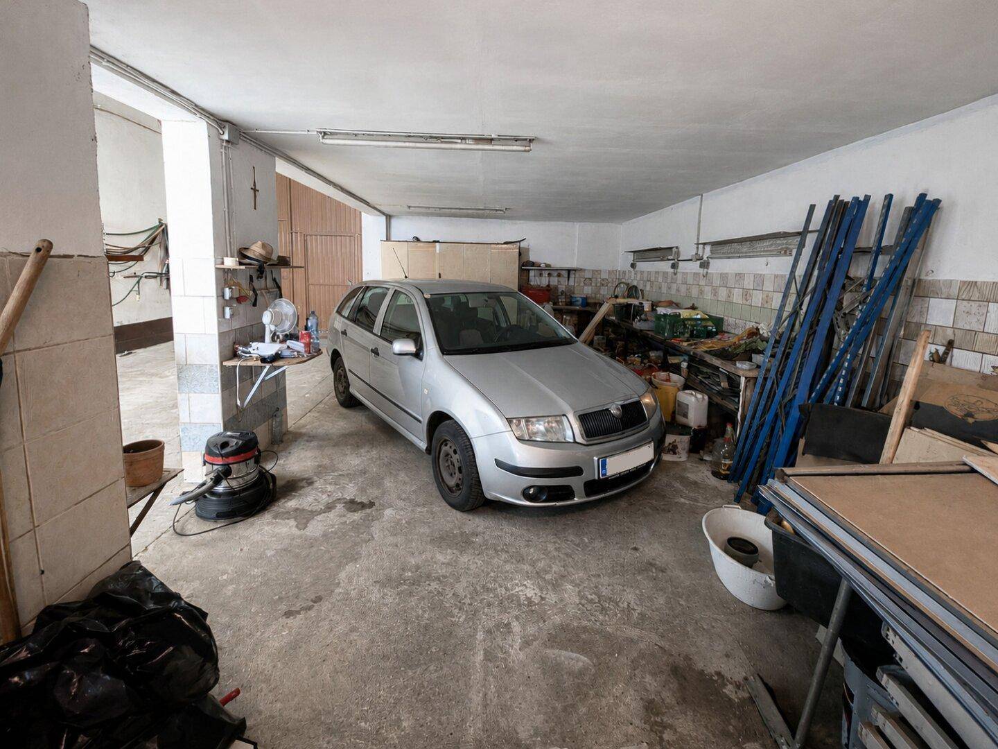 Große Garage mit geparktem Auto, Werkzeugen und Lagerflächen.