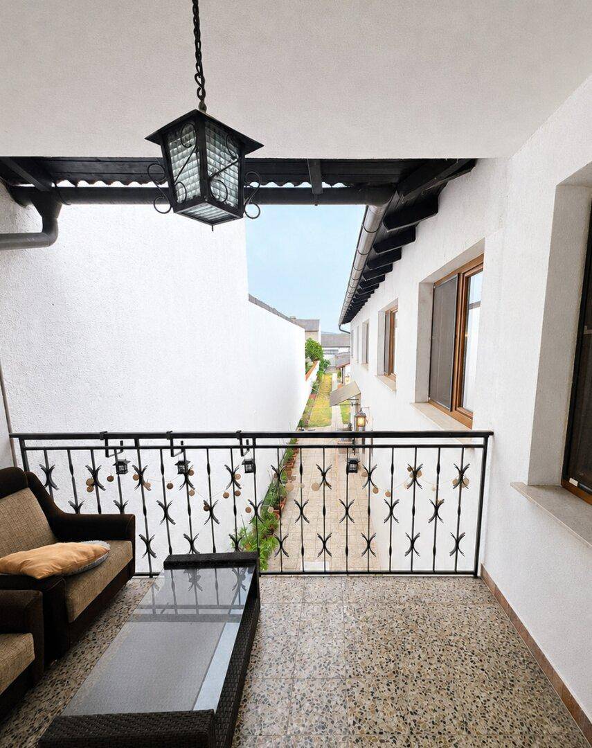 Kleiner Balkon mit schmiedeeisernem Geländer und Sitzgelegenheiten, Blick auf den Hof.