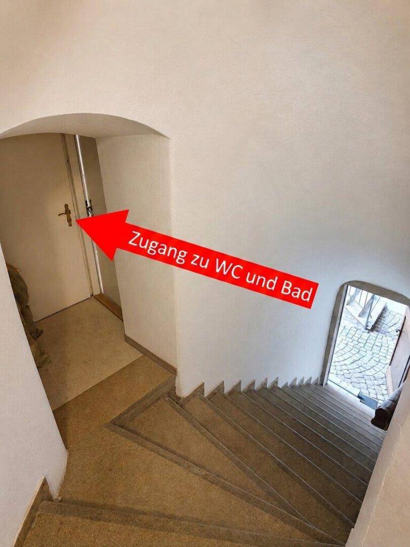 Treppenhaus mit Hinweisschild zum WC und Bad, führt zu weiteren Räumen.