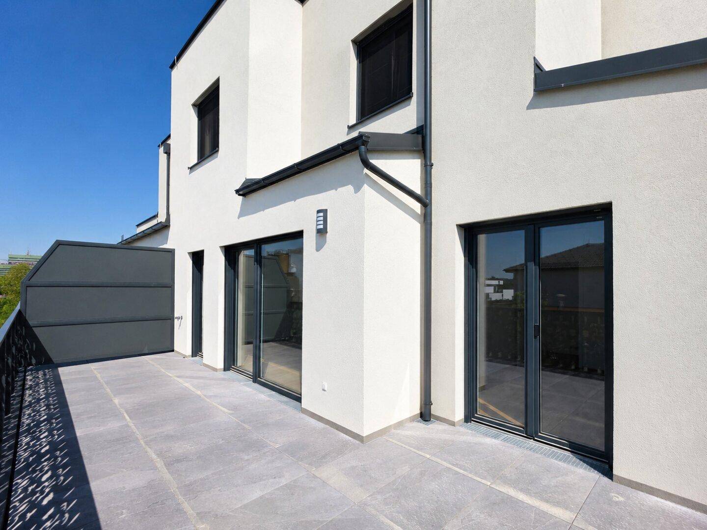 Weitläufige Terrasse mit modernem Design und Blick auf die Umgebung eines Neubaus.