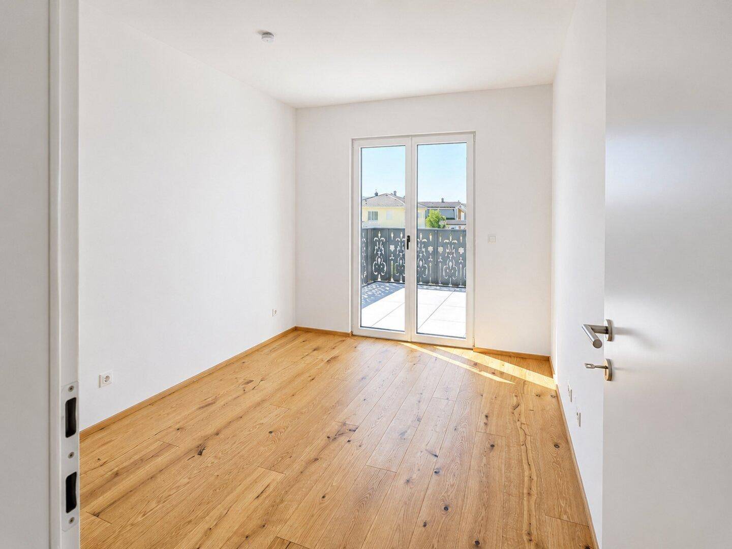 Helles Schlafzimmer mit Holzboden und direktem Zugang zu einer großen Terrasse.