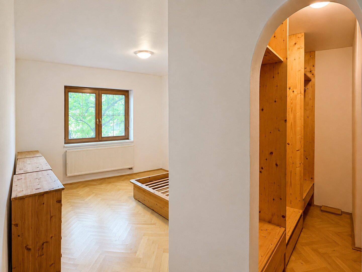 Schlafzimmer mit Fischgrätparkett, Holzbetten und einem praktischen Einbauschrank im Alkoven.