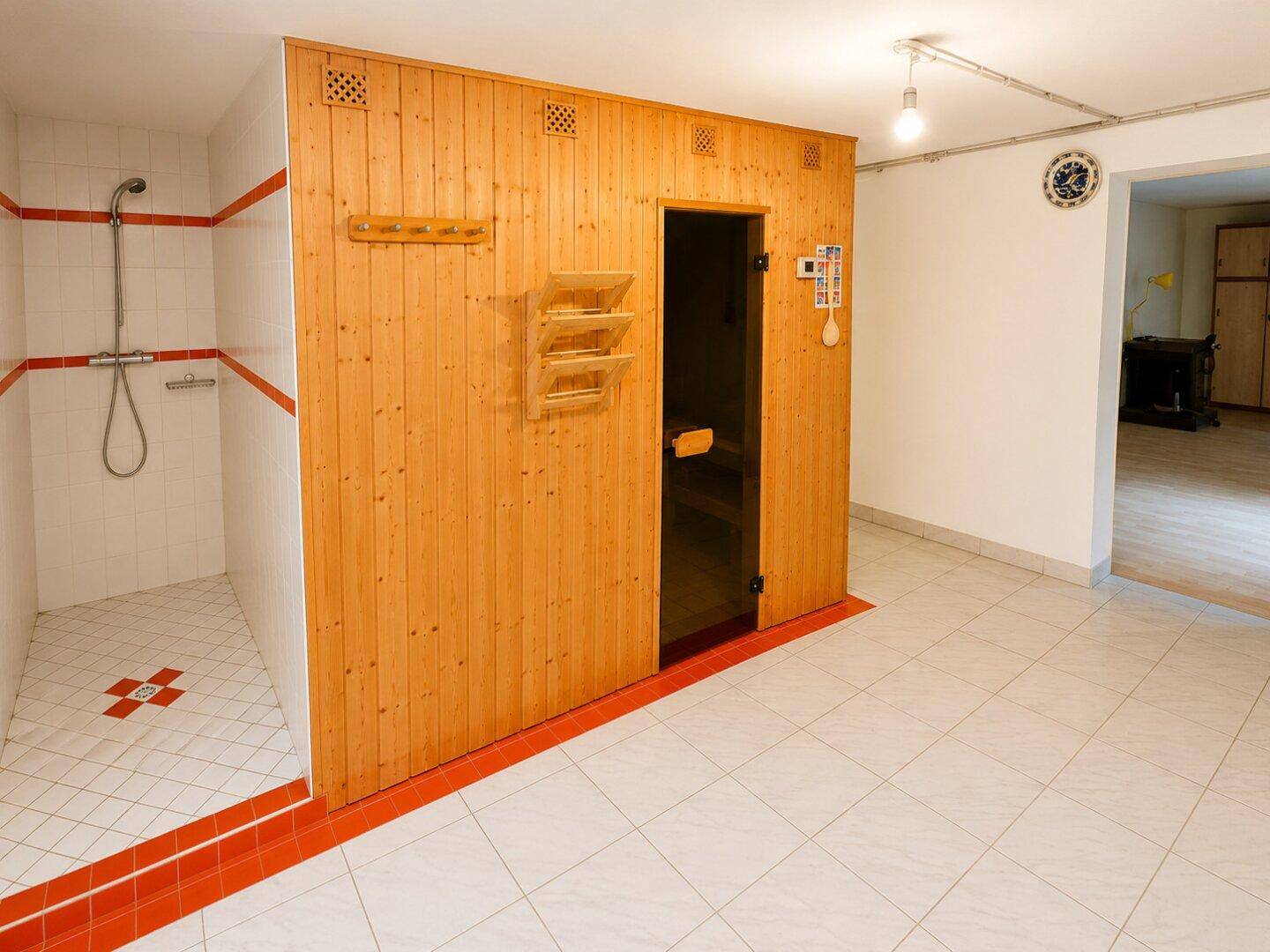 Wellnessbereich mit holzverkleideter Sauna und angrenzender Dusche, ideal zur Entspannung.