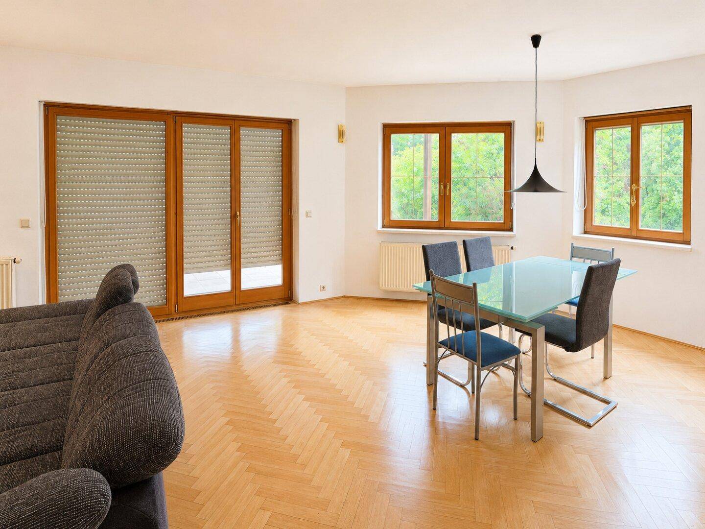 Heller Essbereich mit Glastisch, Stühlen und Zugang zu einer Terrasse durch große Fenstertüren.