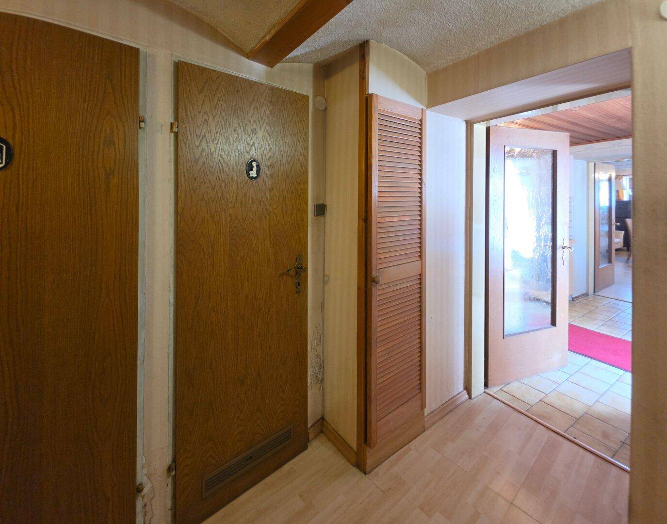Flur mit Holztüren, Laminatboden und Durchgang zu weiteren Räumen.