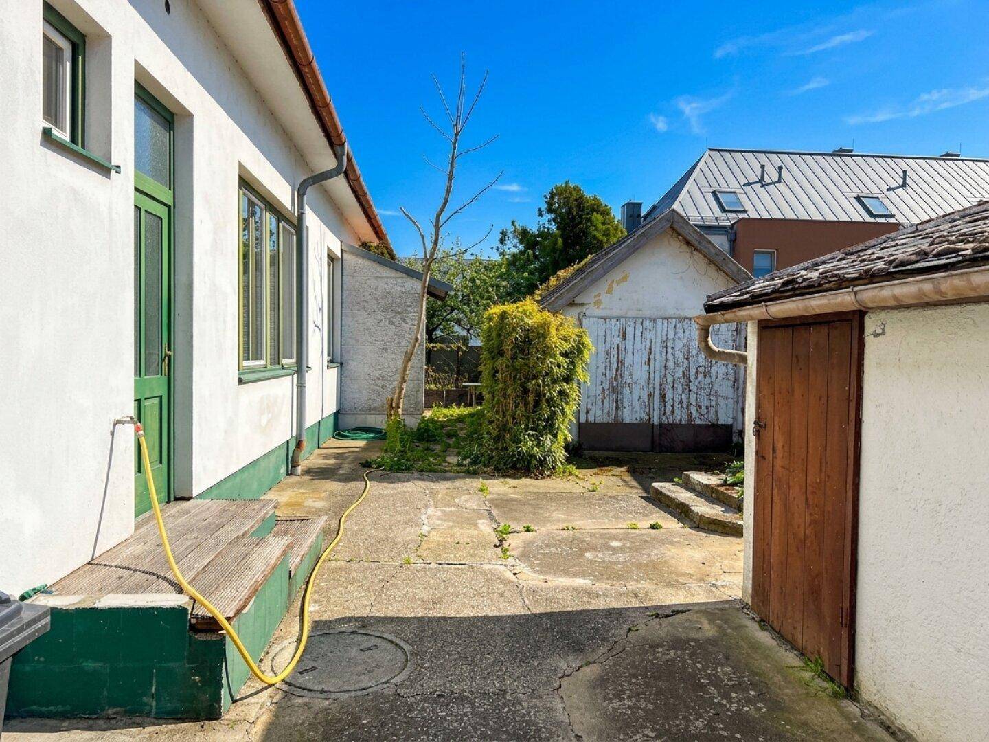 Gepflasterter Innenhof mit Sitzbank und Zugang zu Nebengebäuden, ideal für den Außenbereich.