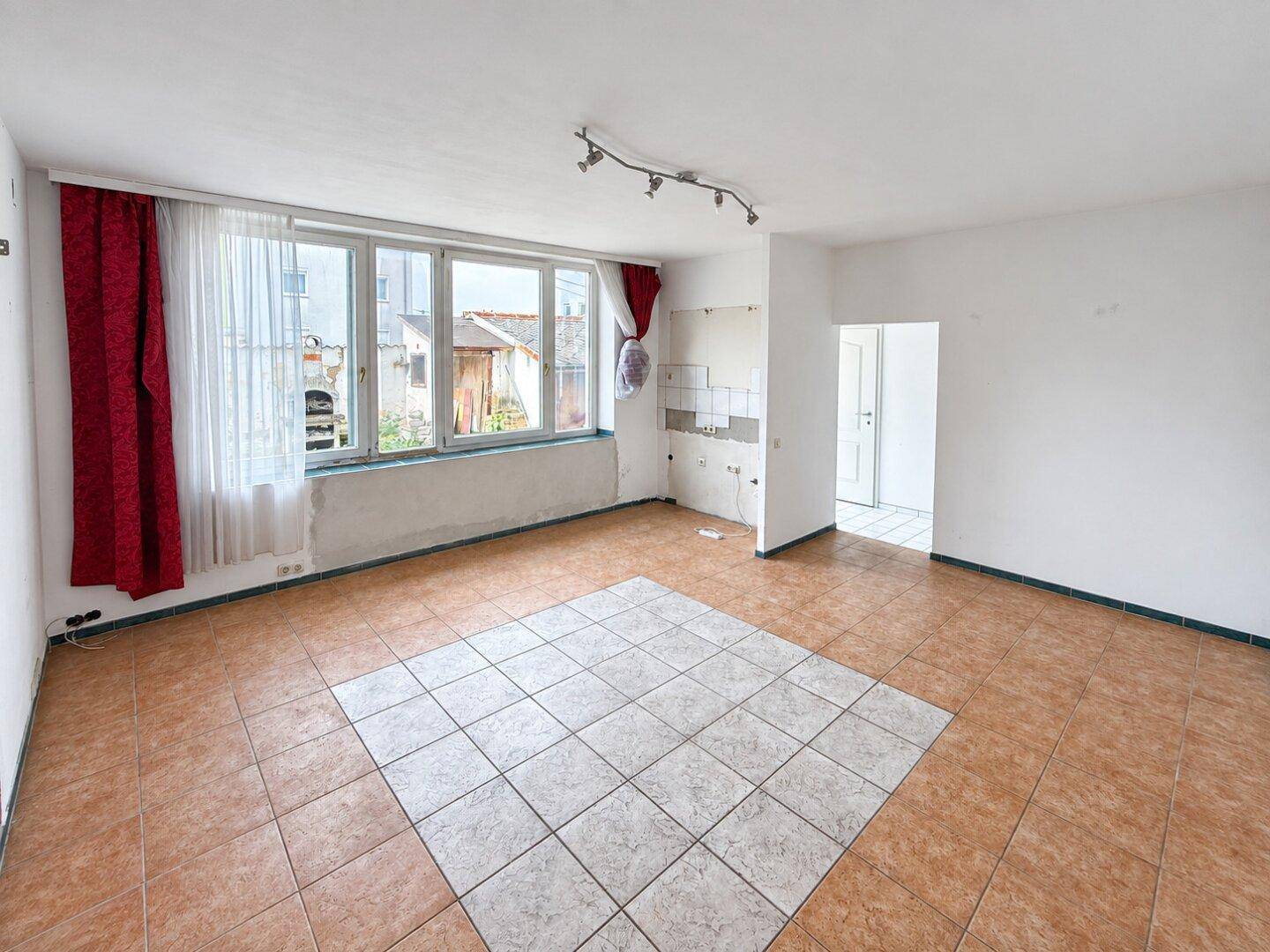 Geräumiger Wohnraum mit Fliesenboden und großen Fenstern, bietet vielseitige Gestaltungsmöglichkeiten.