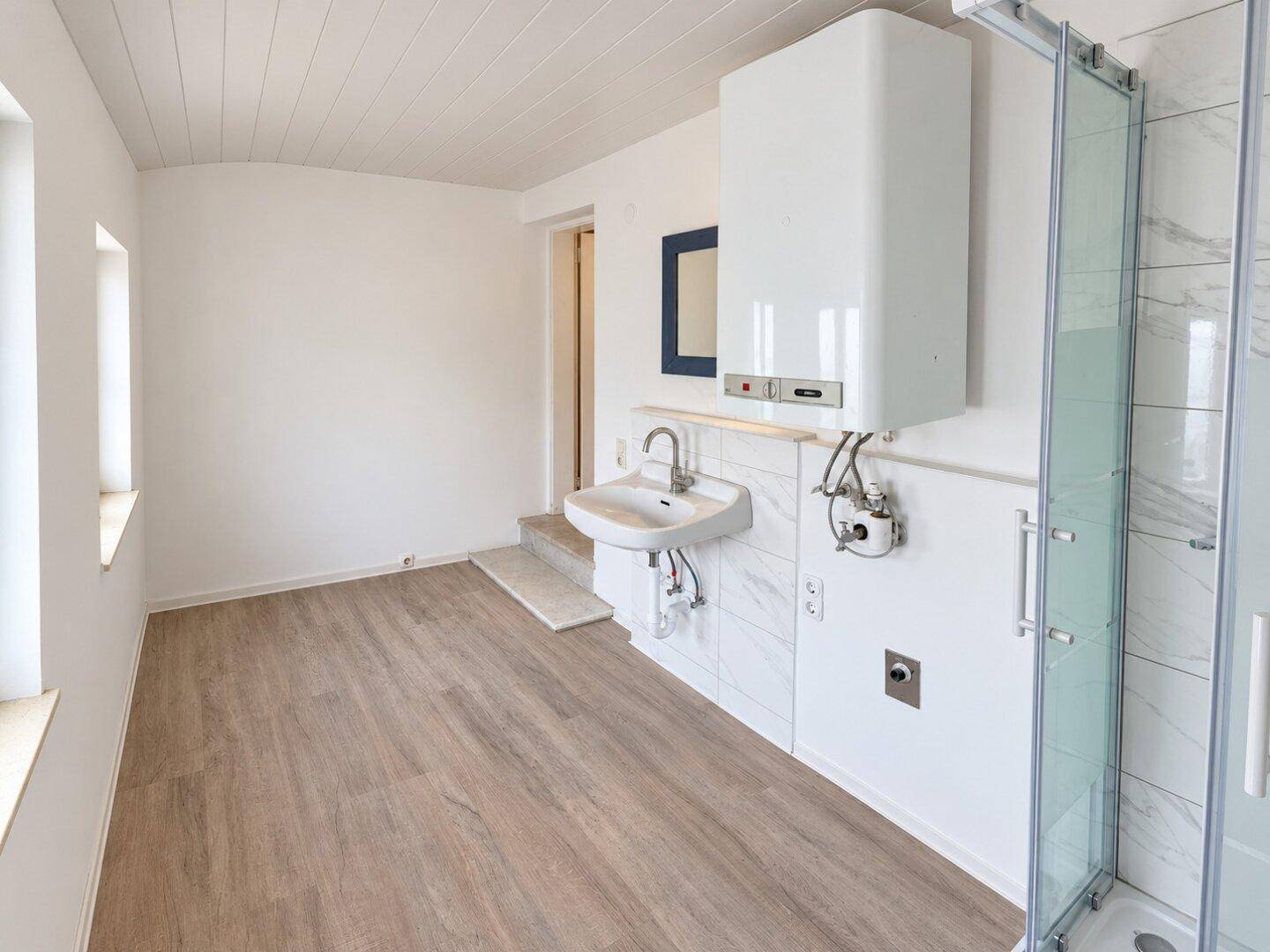Helles Badezimmer mit Duschkabine, Waschbecken und Fenster für Tageslicht.