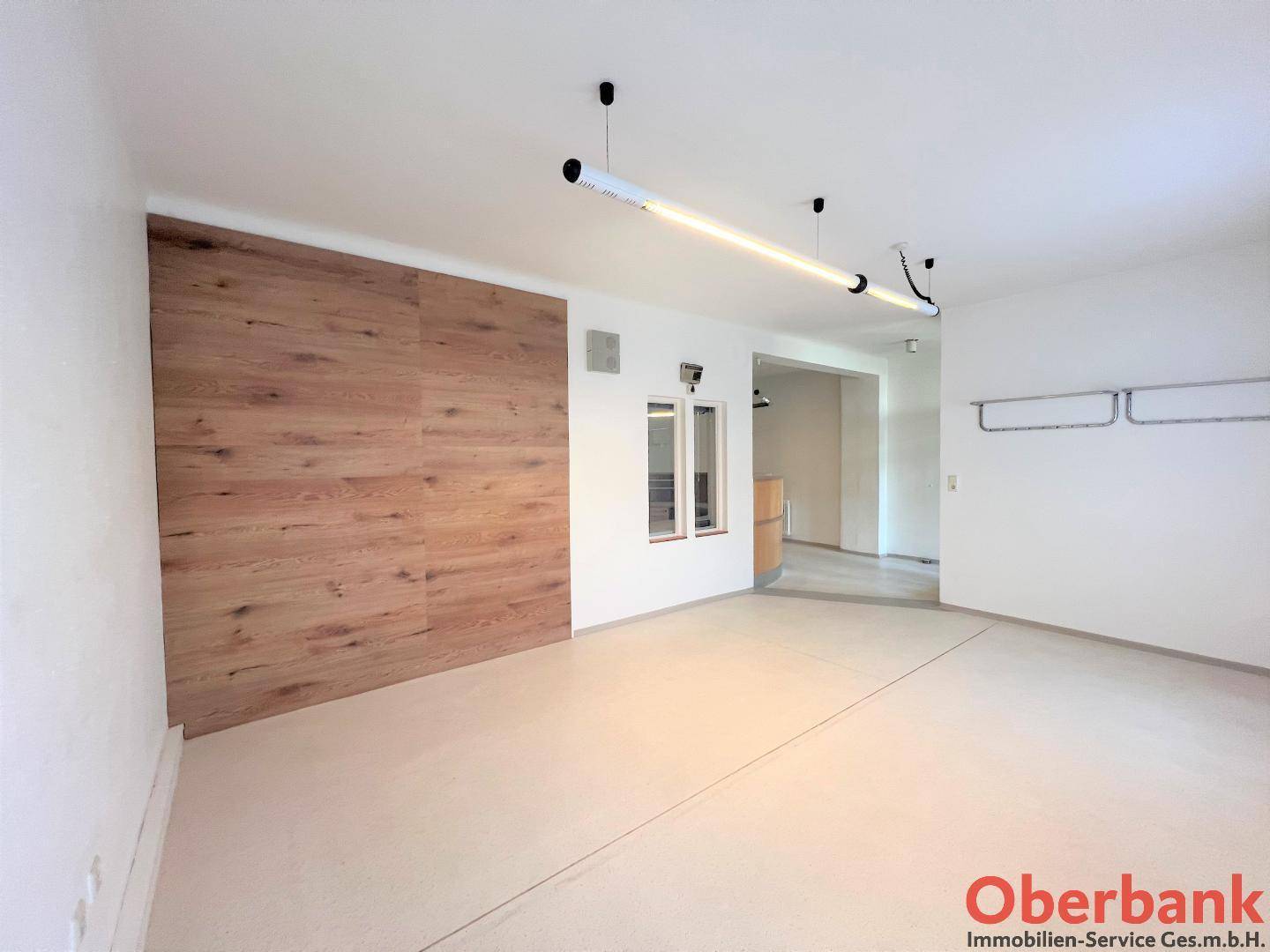 Geräumiger Büroraum mit einer Holzwandverkleidung und moderner Deckenbeleuchtung.