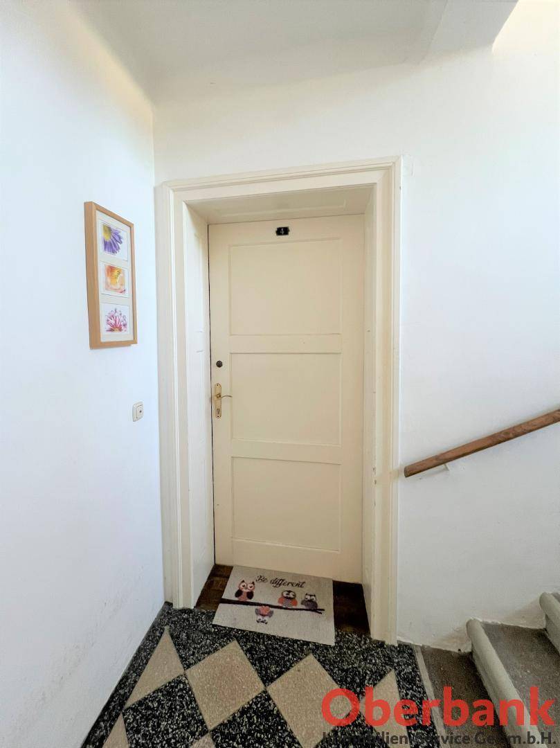 Eingangstür einer Wohnung im Treppenhaus mit gemustertem Fliesenboden.