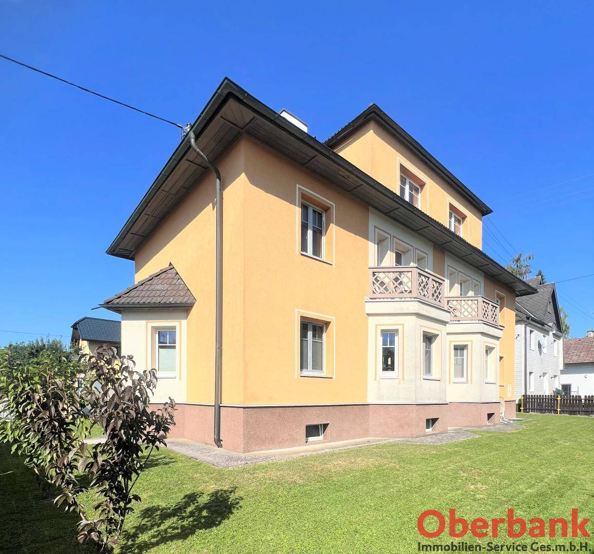 Rückansicht des Hauses mit Balkonen und einem gepflegten Rasenbereich im Garten.