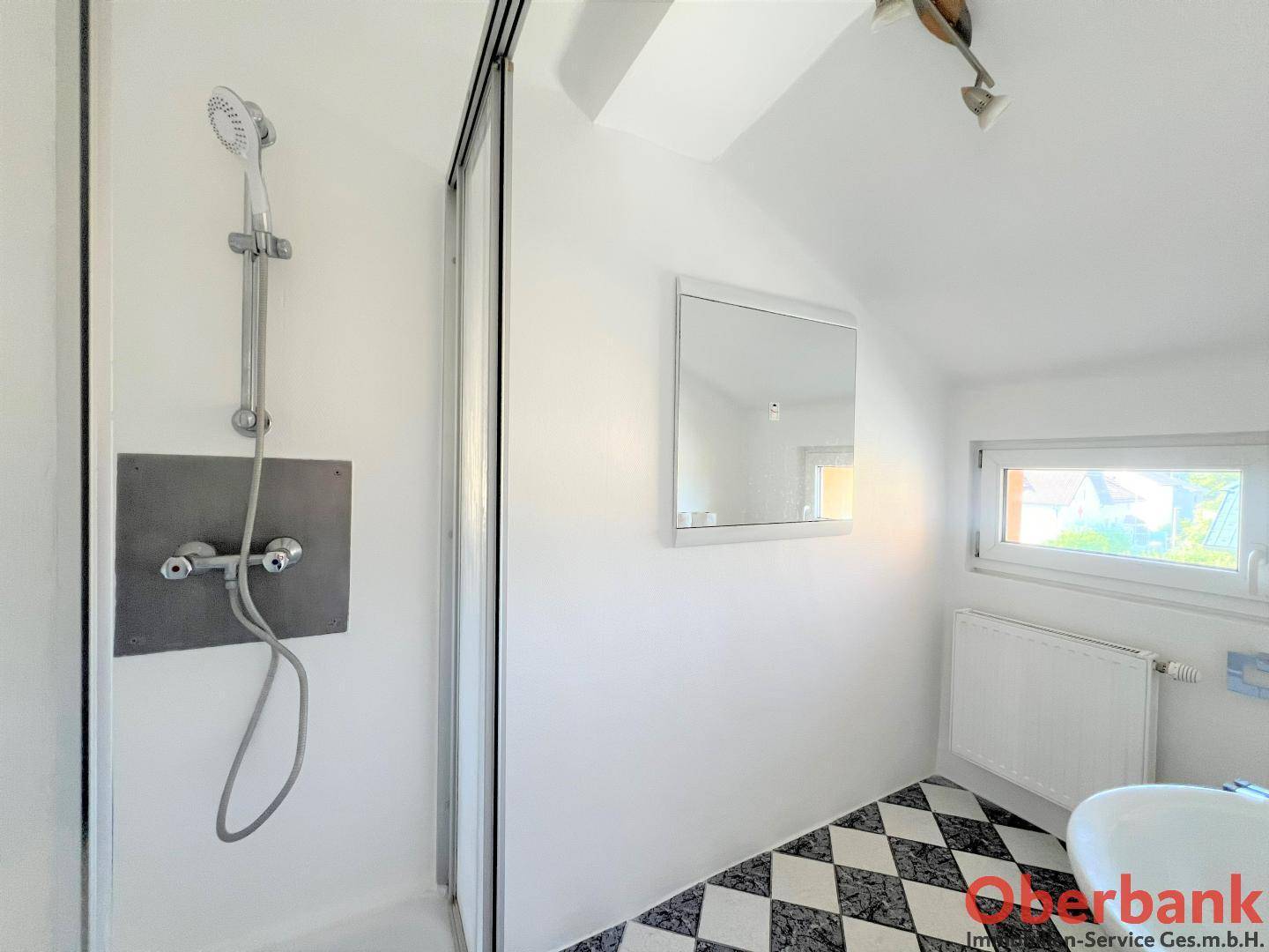 Modernes Badezimmer mit Duschkabine, Waschbecken und schwarz-weißem Fliesenboden.