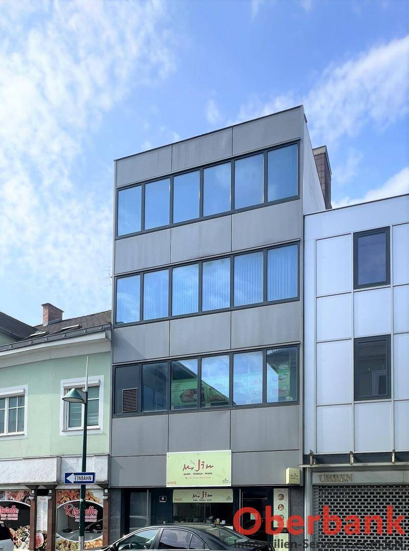 Moderne Geschäftsfassade mit großen Glasfenstern in einem städtischen Umfeld.