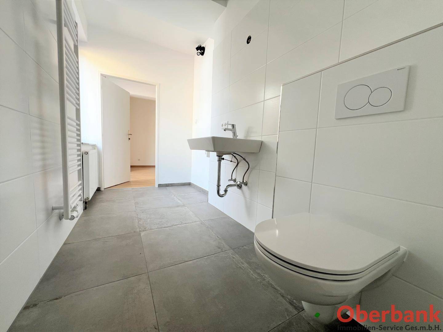 Zeitgemäßes Badezimmer mit WC, Waschbecken und großformatigen Fliesen, hell und funktional.